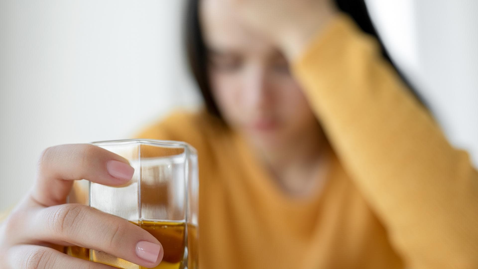 Verzweifelte Frau mit einem Glas Alkohol in der Hand Verzweifelte Frau mit einem Glas Alkohol in der Hand