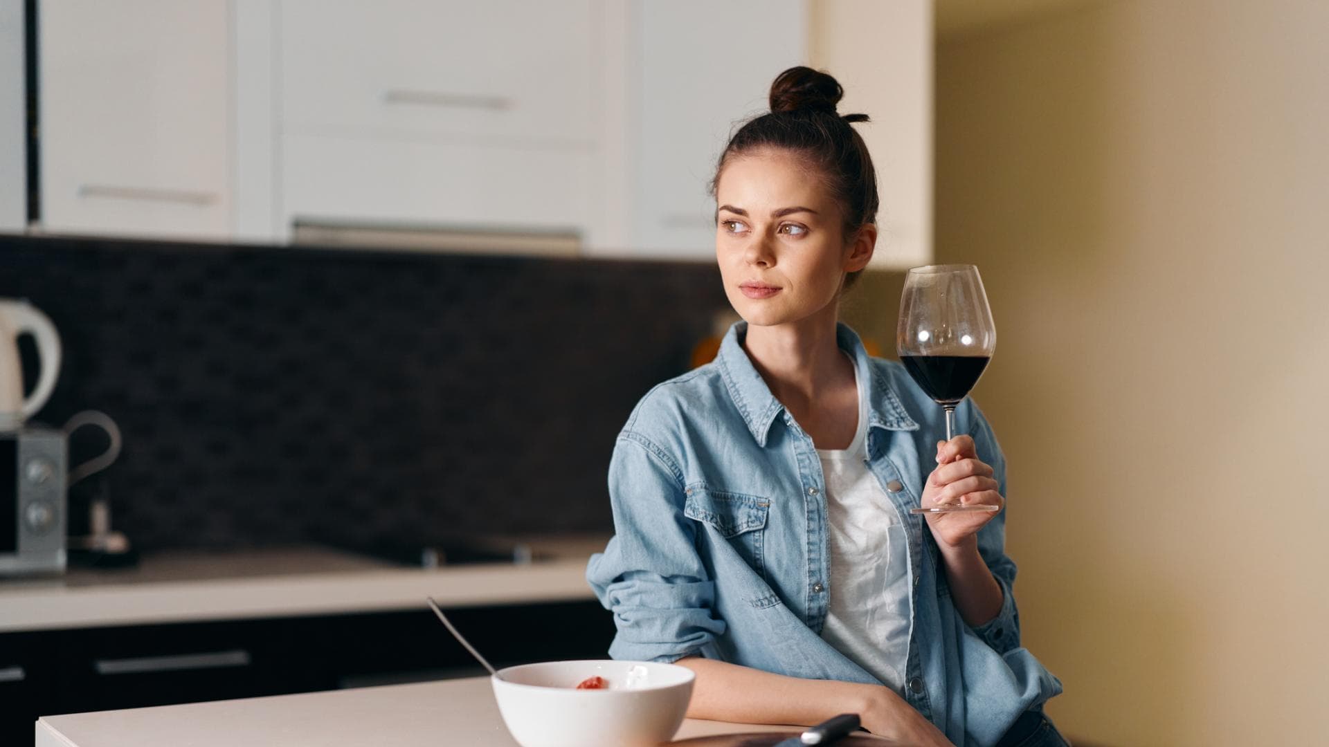 Frau steht in der Küche und trinkt Wein Frau steht in der Küche und trinkt Wein