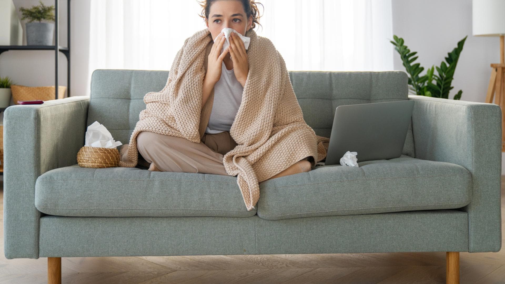 Erkältete Frau sitzt auf Sofa