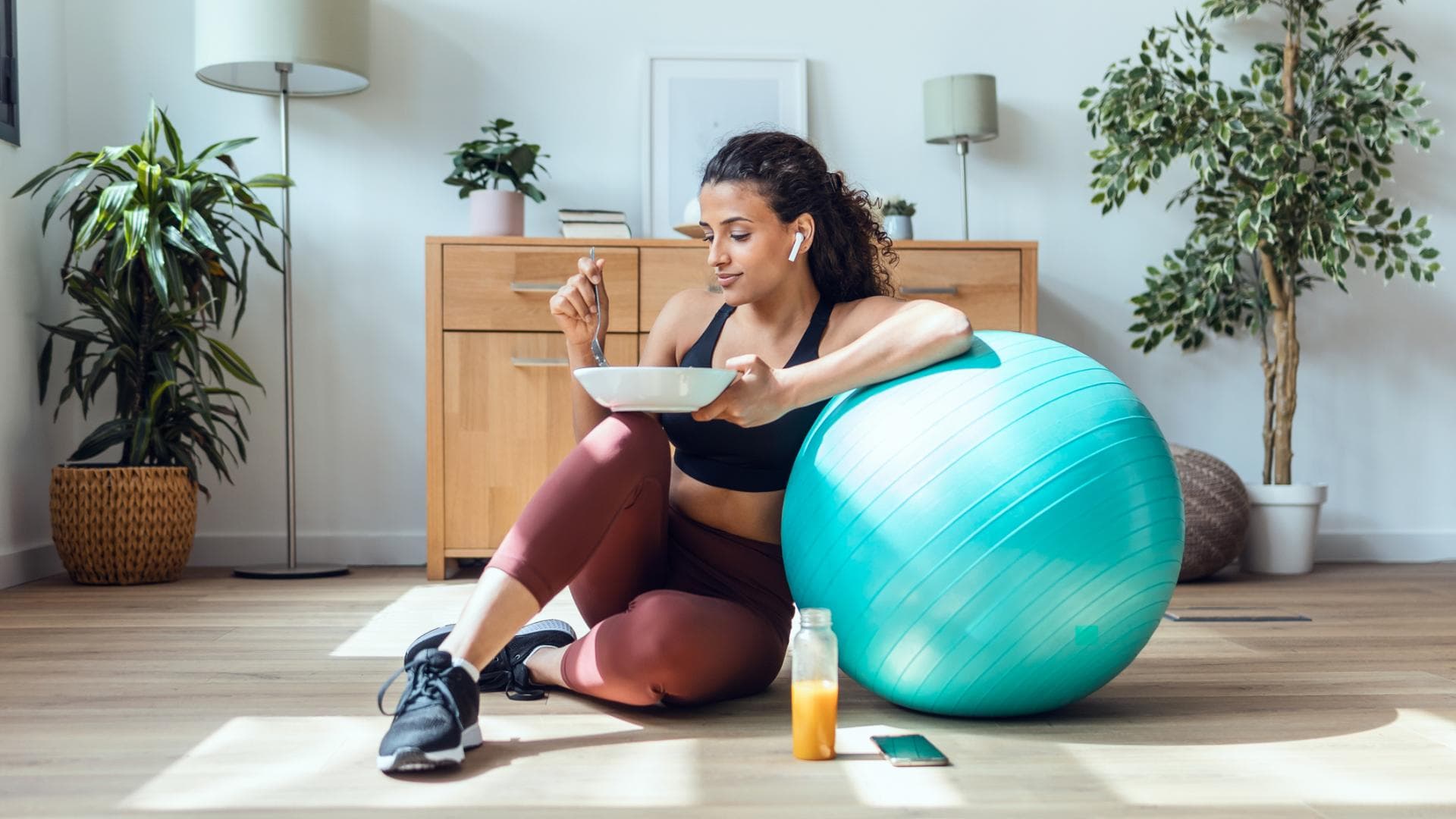 Frau sitzt neben Gymnastikball mit gesundem Essen Frau sitzt neben Gymnastikball mit gesundem Essen