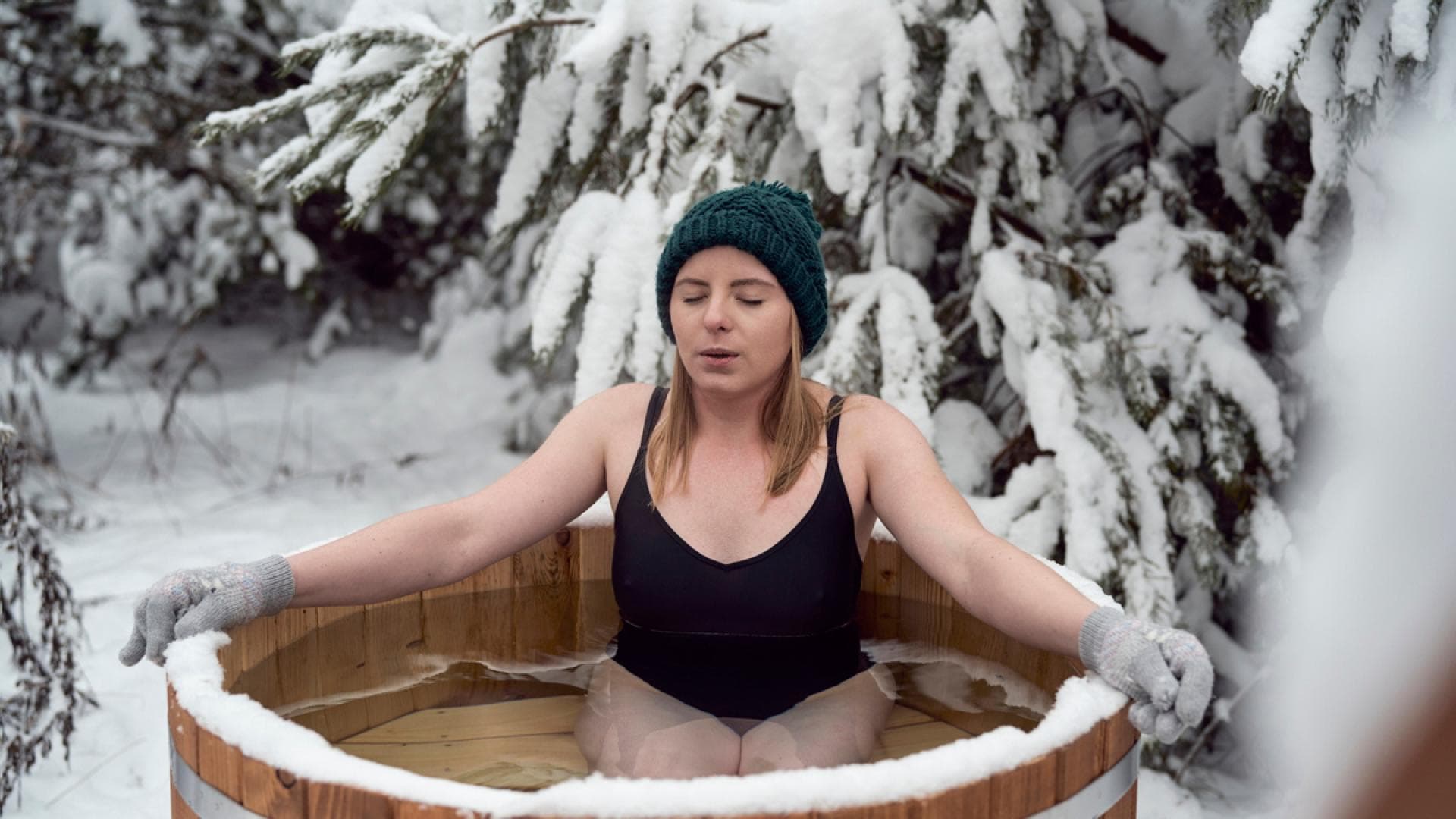 Frau nimmt ein Eisbad in einer Eistonne Frau nimmt ein Eisbad in einer Eistonne