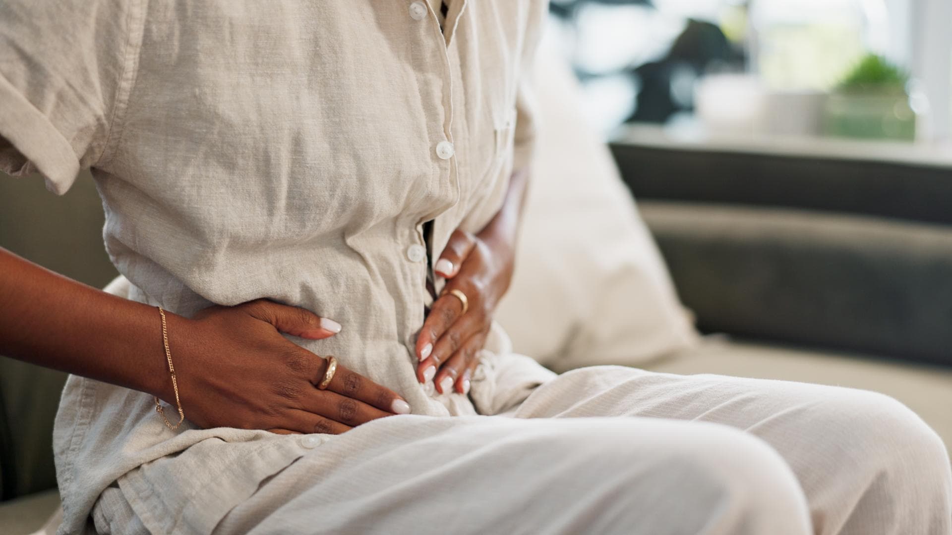 Frau sitzt auf dem Sofa und hält sich den Bauch. Frau sitzt auf dem Sofa und hält sich den Bauch.