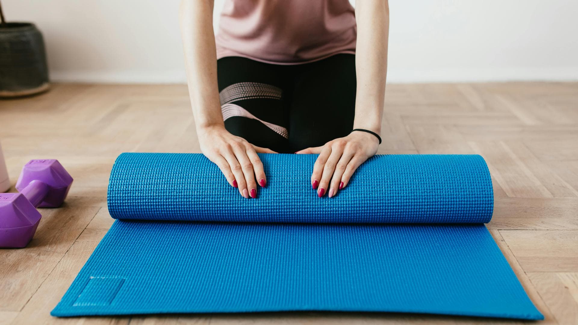 Frau rollt Sportmatte zusammen Frau rollt Sportmatte zusammen