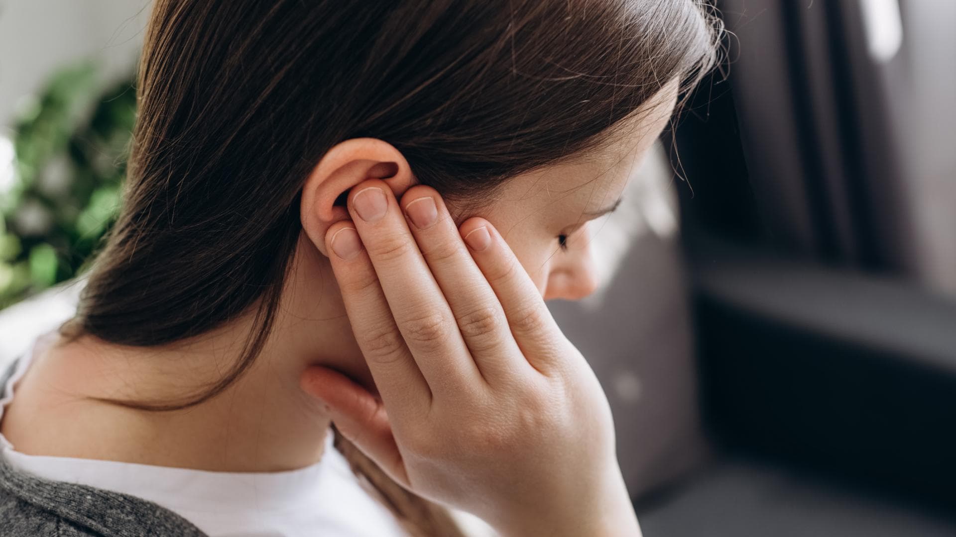 Frau fasst sich ans Ohr Frau fasst sich ans Ohr