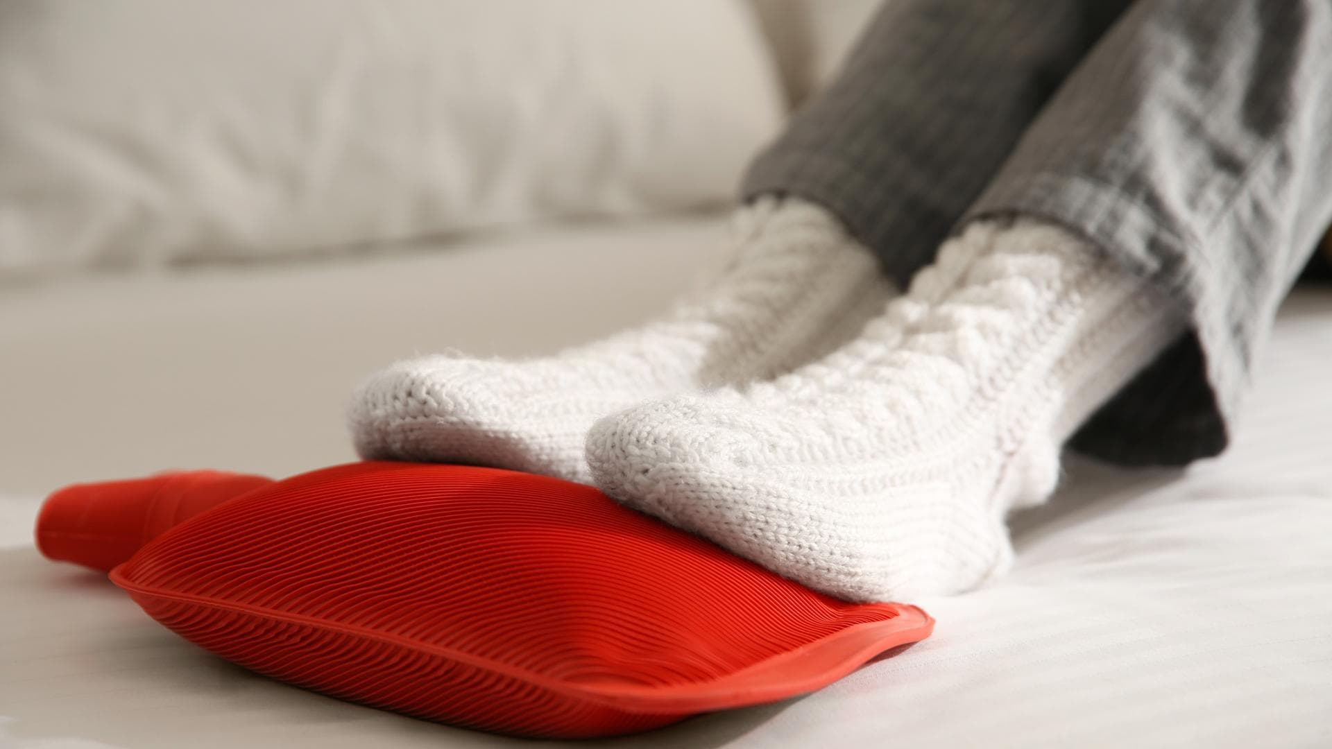 Füße in Socken liegen auf Wärmflasche Füße in Socken liegen auf Wärmflasche