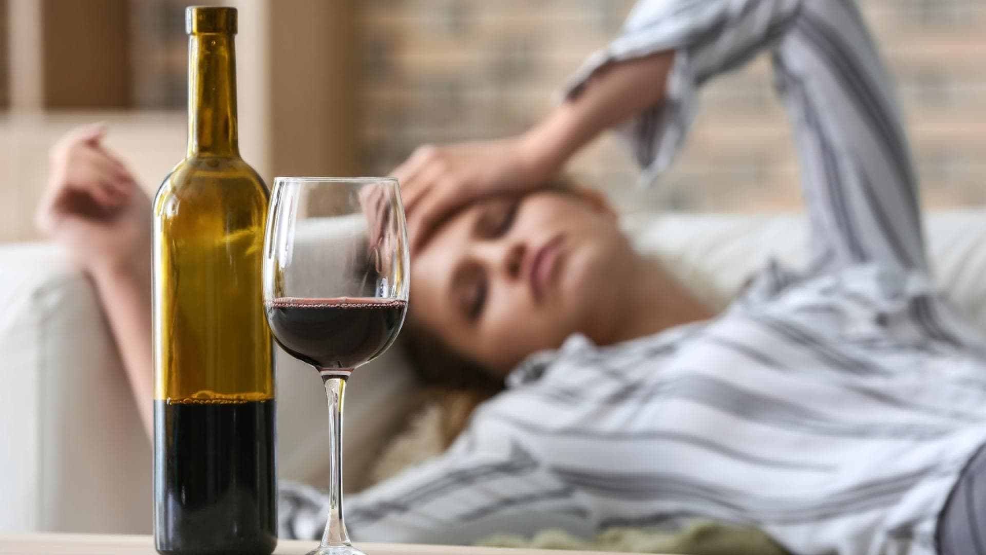 Offene Flasche Rotwein, Frau liegt auf einem Sofa Offene Flasche Rotwein, Frau liegt auf einem Sofa