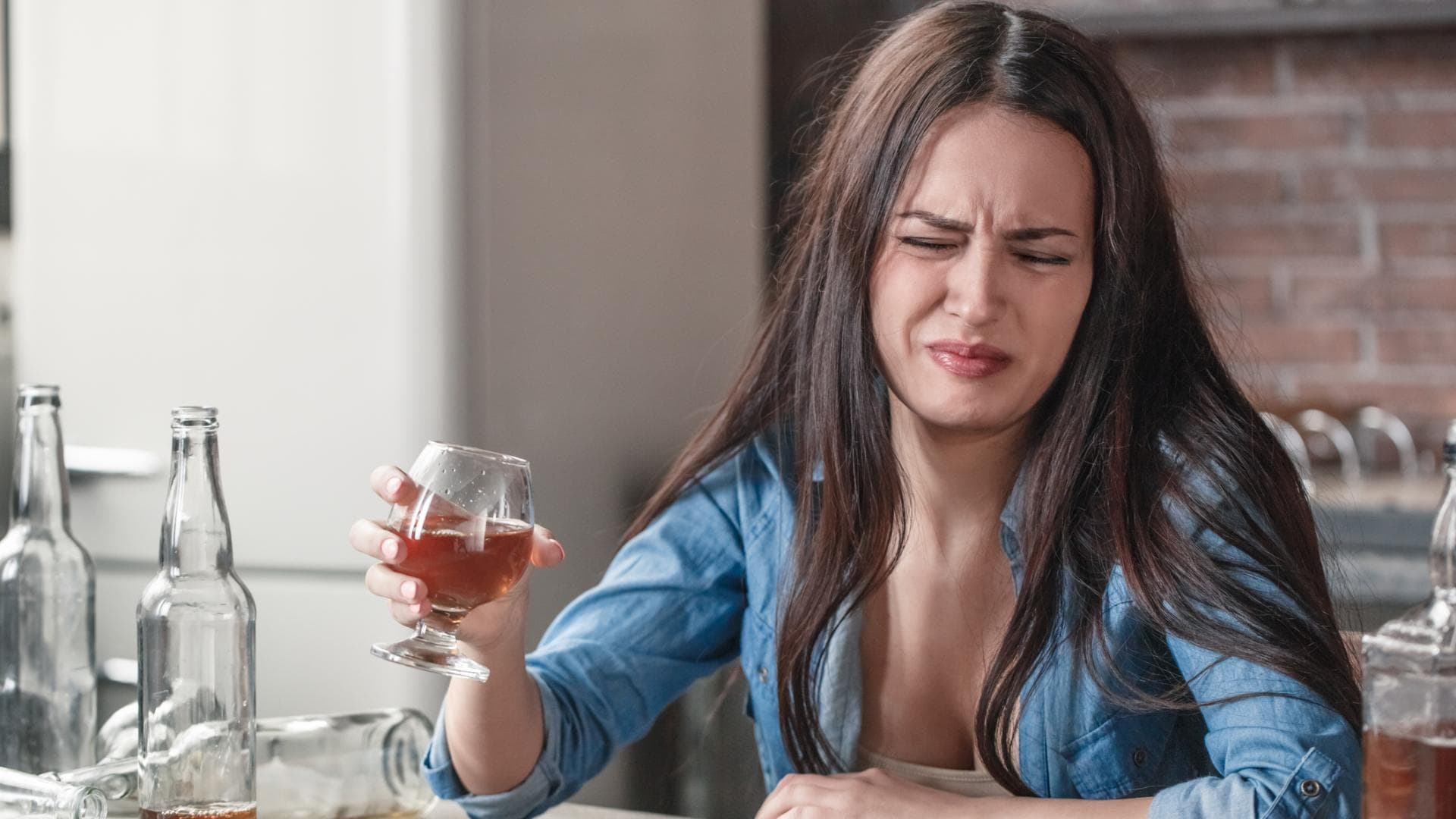 Frau verzieht das Gesicht und hält ein Glas in der Hand