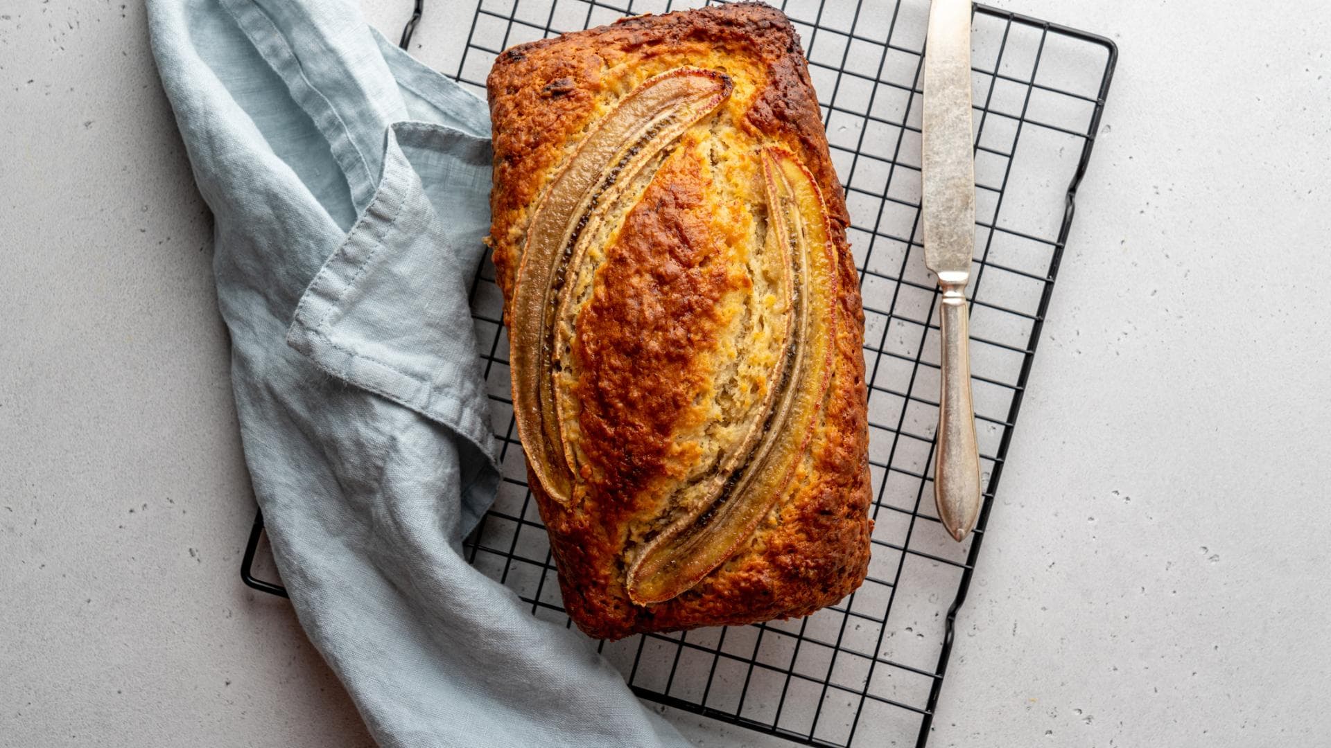 Bananenbrot angerichtet mit einem Messer auf einem Rost