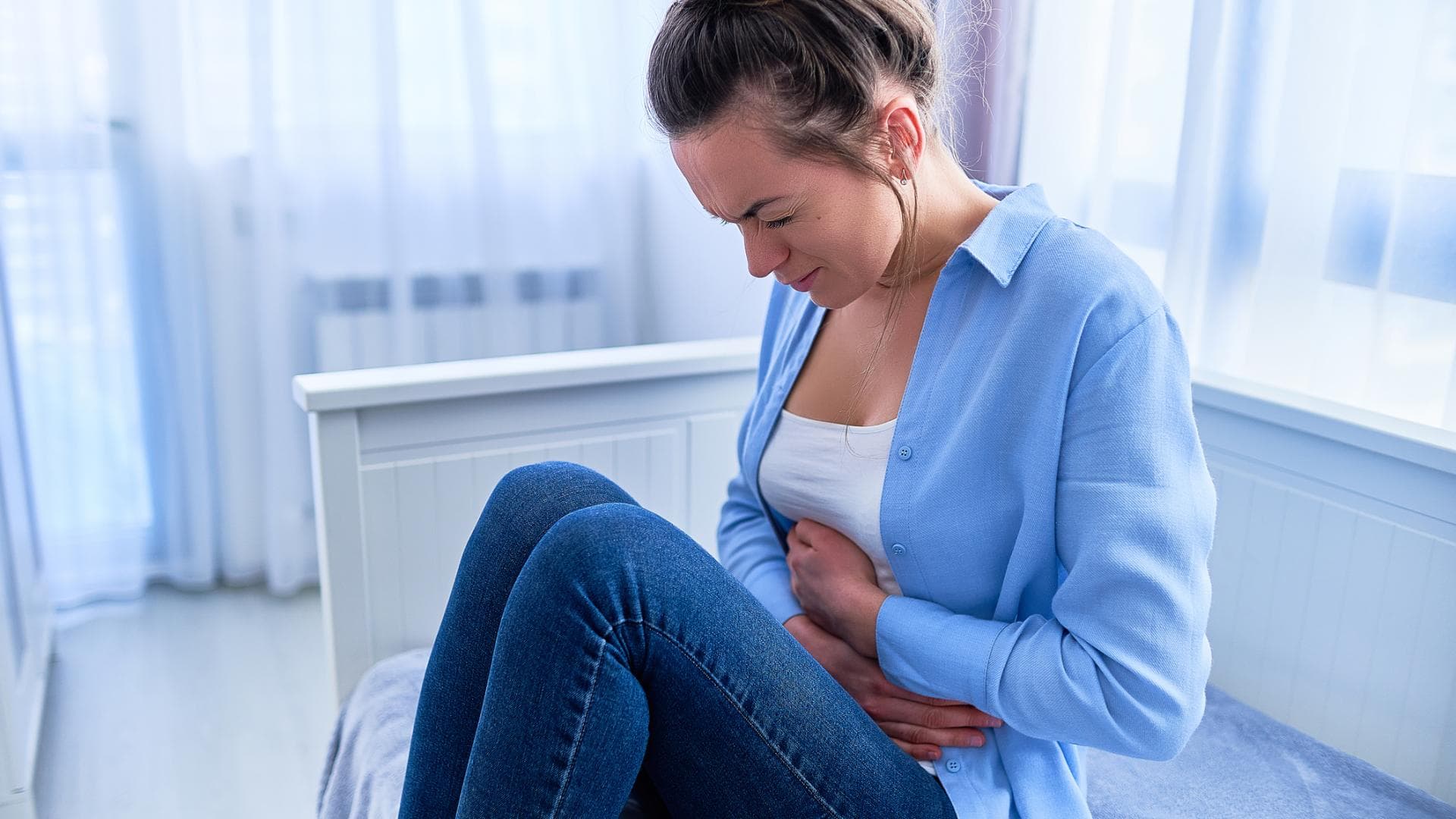 Frau fasst sich an den Bauch und hat Schmerzen Frau fasst sich an den schmerzenden Bauch