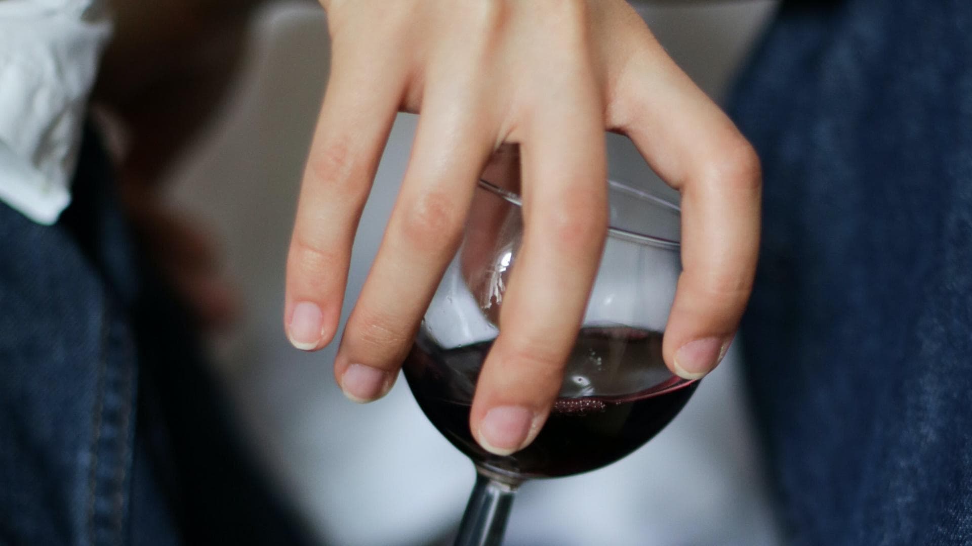 Alkohol - auch das Glas Rotwein am Abend - ist nicht gerade gesund Eine Frau hält lässig ein Glas Wein in der Hand