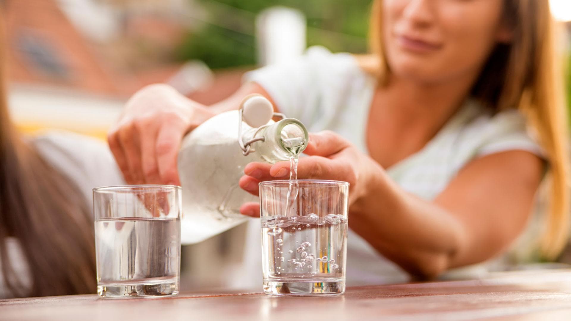 Frau gießt Wasser in Glas ein Frau gießt Wasser in Glas ein