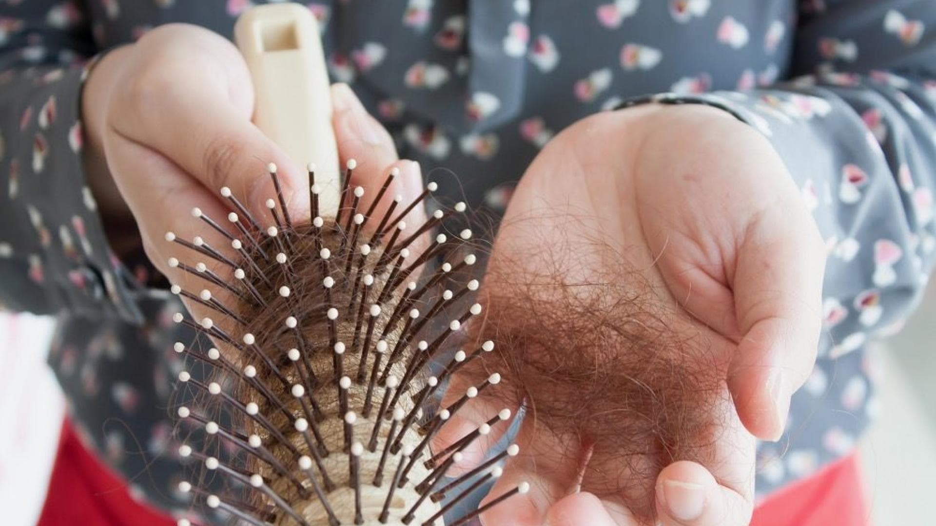 Frau hält ein Haarknäuel und ihre Bürste in der Hand.