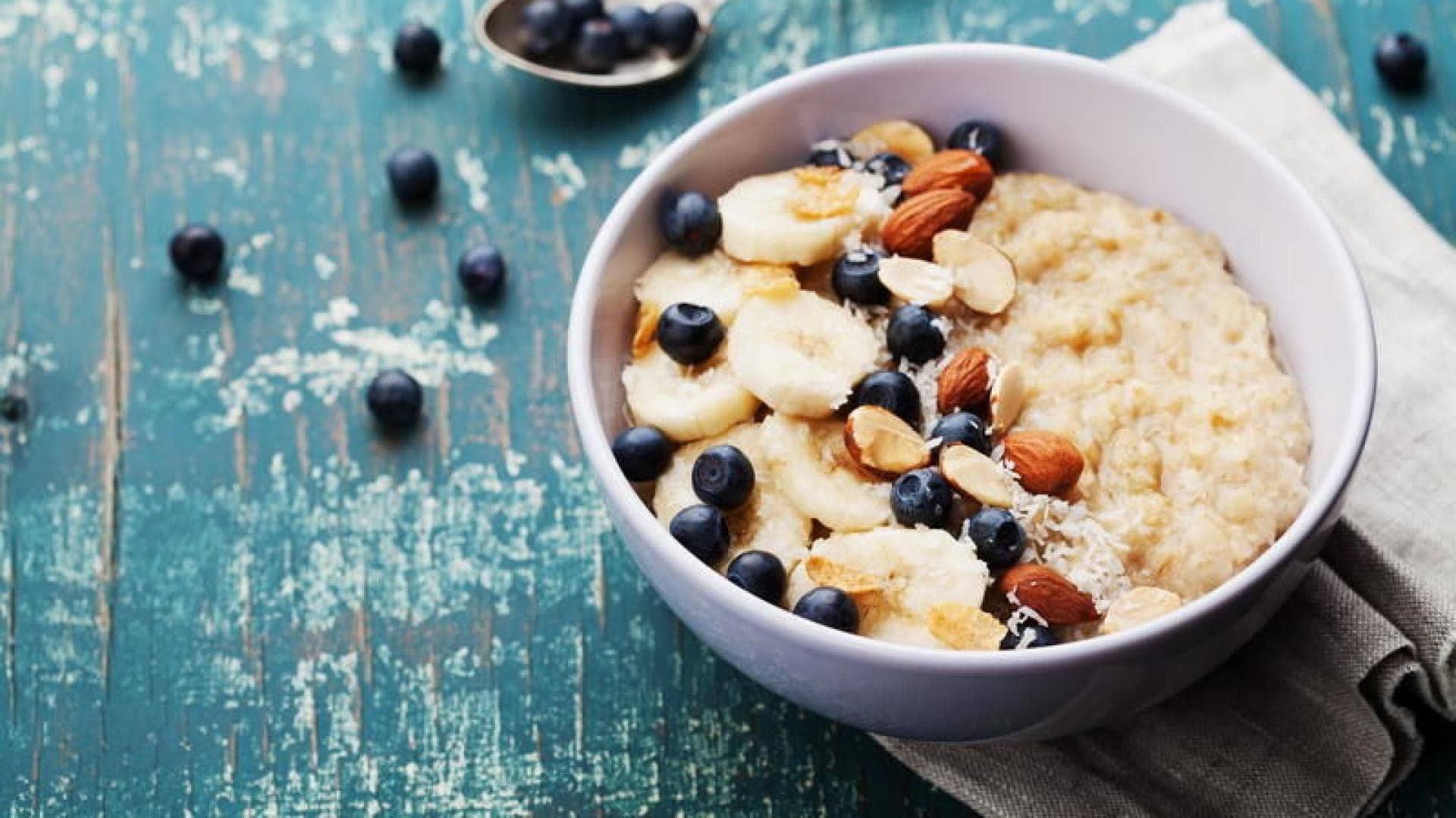 Overnight-Oats ist einer Schüssel mit Blaubeeren, Banane und Mandeln.