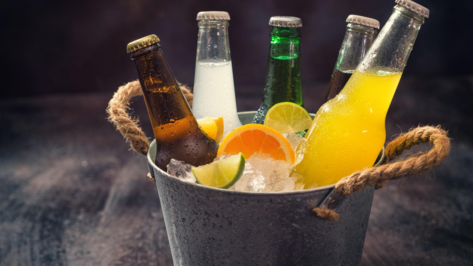 Fünf Flaschen Limonade in einem Eimer mit Eiswürfeln