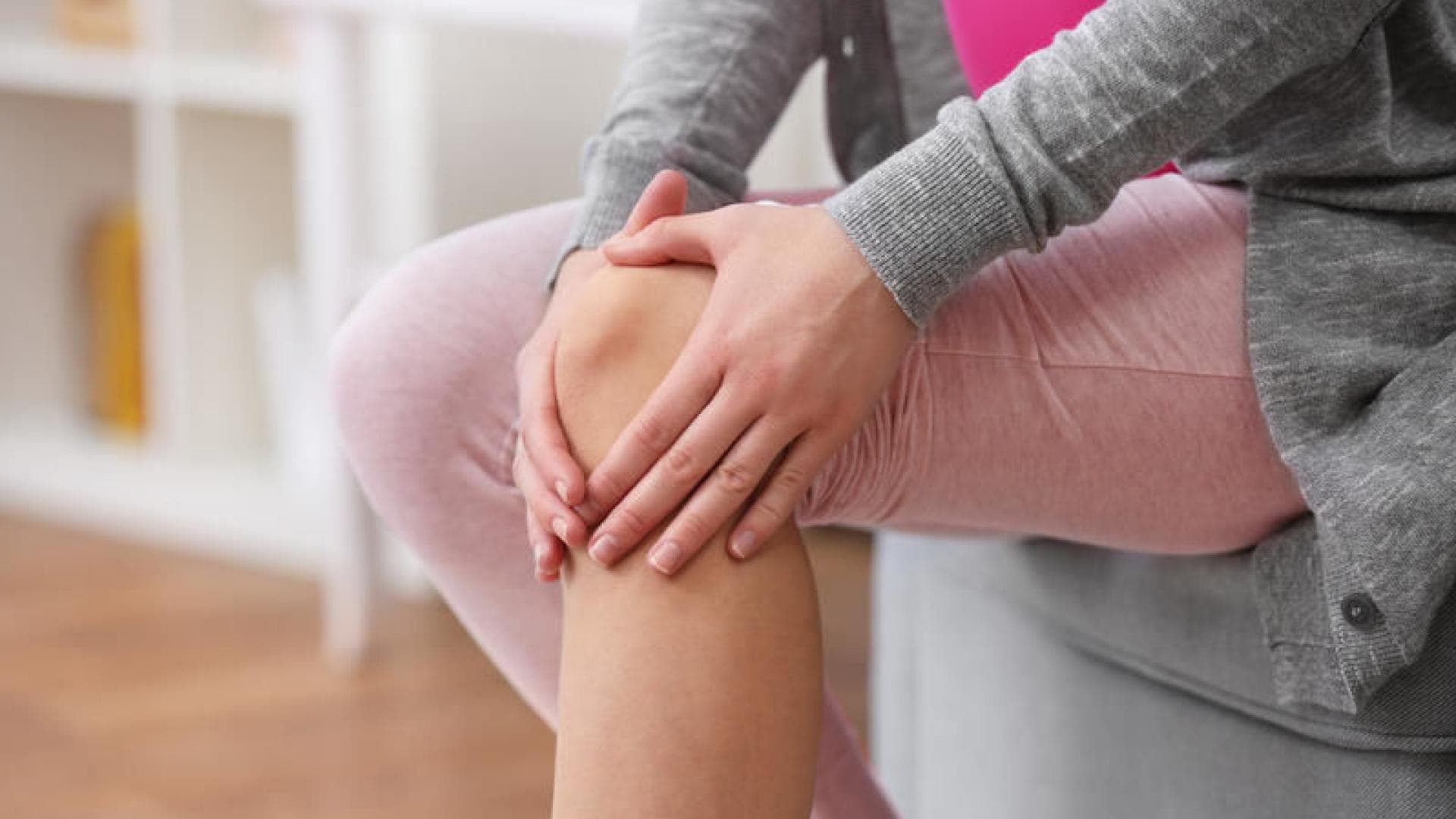 Frau legt Hände auf ihr Knie