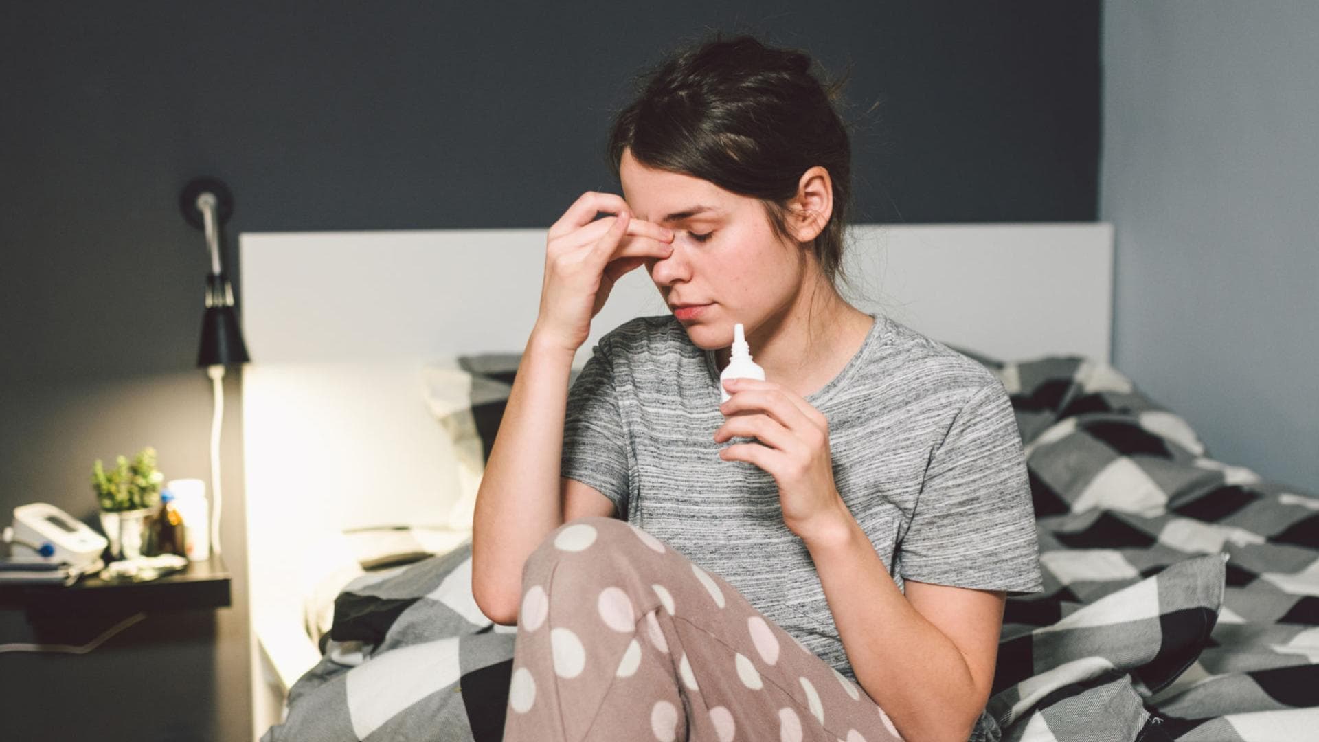 Frau mit Nasenspray im Bett