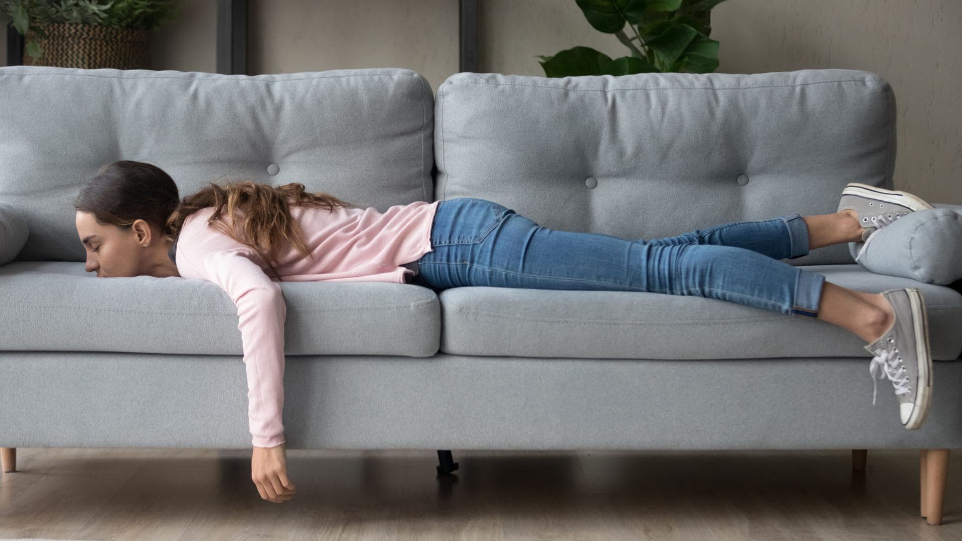 Boreout Symptom: Frau liegt bäuchlings auf dem Sofa