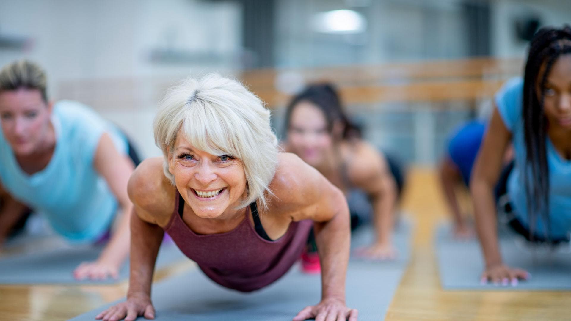 Ältere Frau im Sportkurs macht Liegestütze