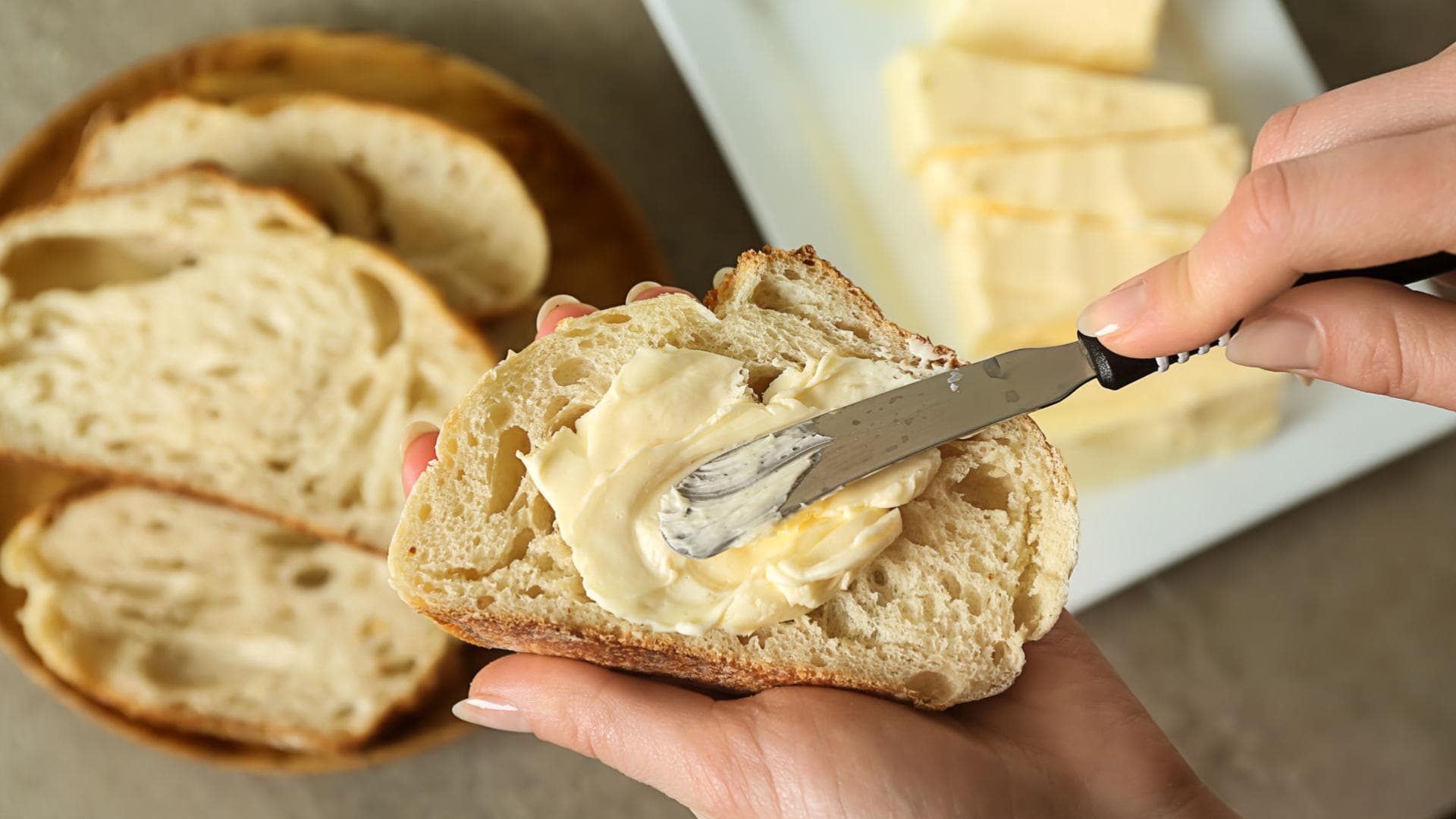 Frau schmiert Butter auf eine Scheibe Brot Frau schmiert Butter auf eine Scheibe Brot