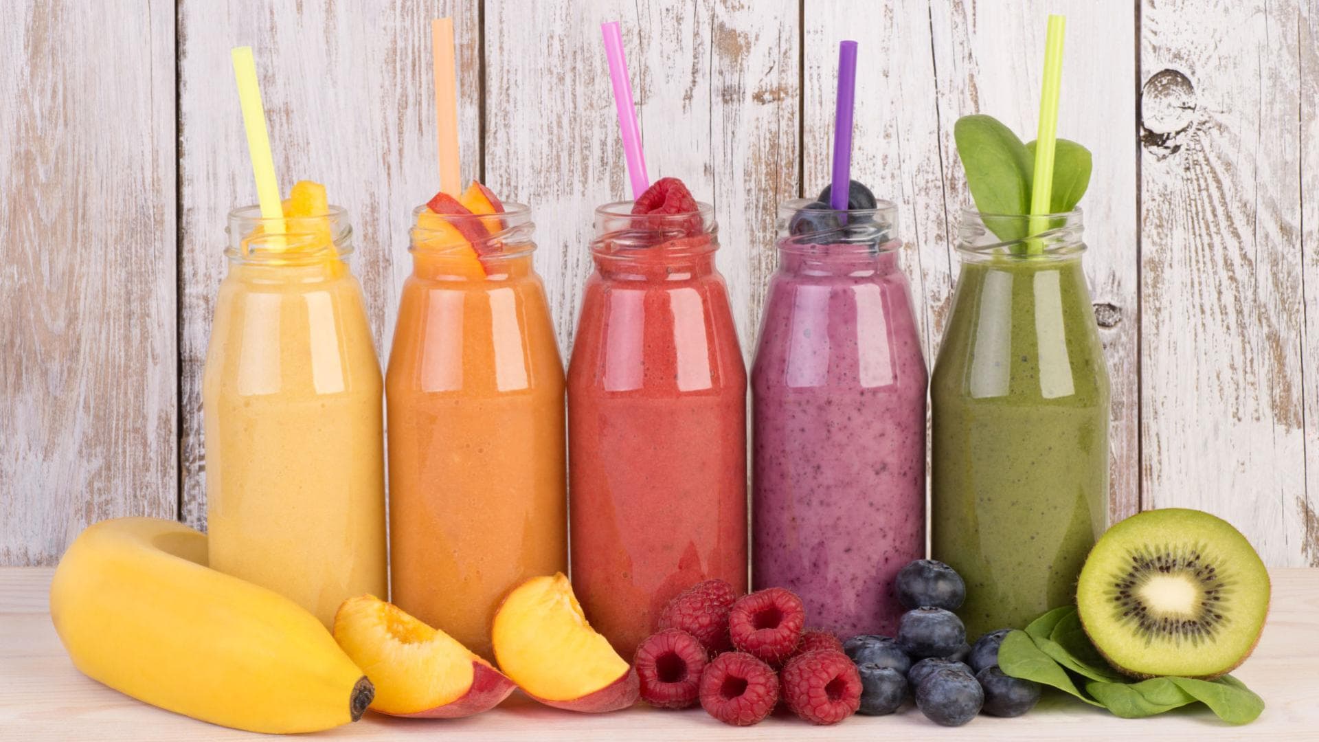 Fünf verschiedene bunte Smoothies in Flaschen 