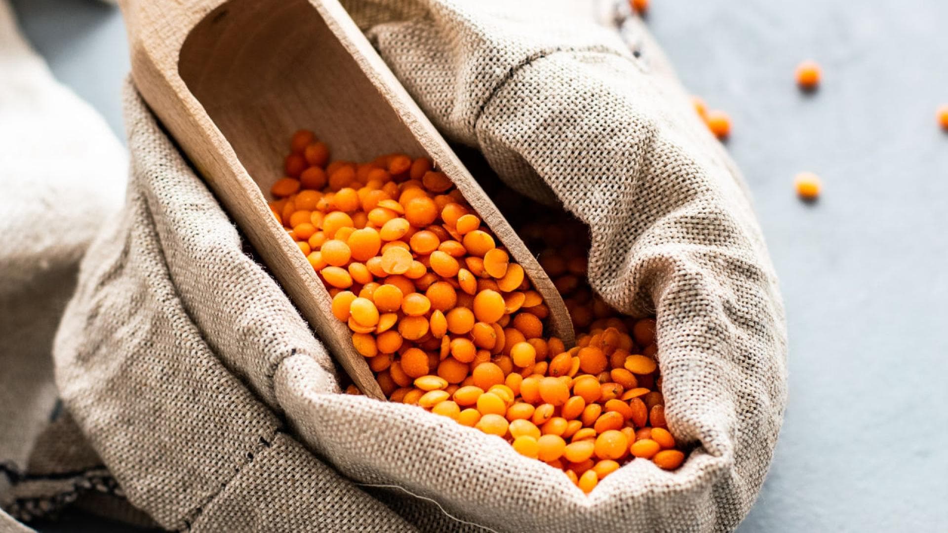 Pflanzliche Proteine sind in Hülsenfrüchten, Sojaprodukten, Vollkornprodukten, Nüssen und Samen enthalten. Rote Linsen in einem Säckchen