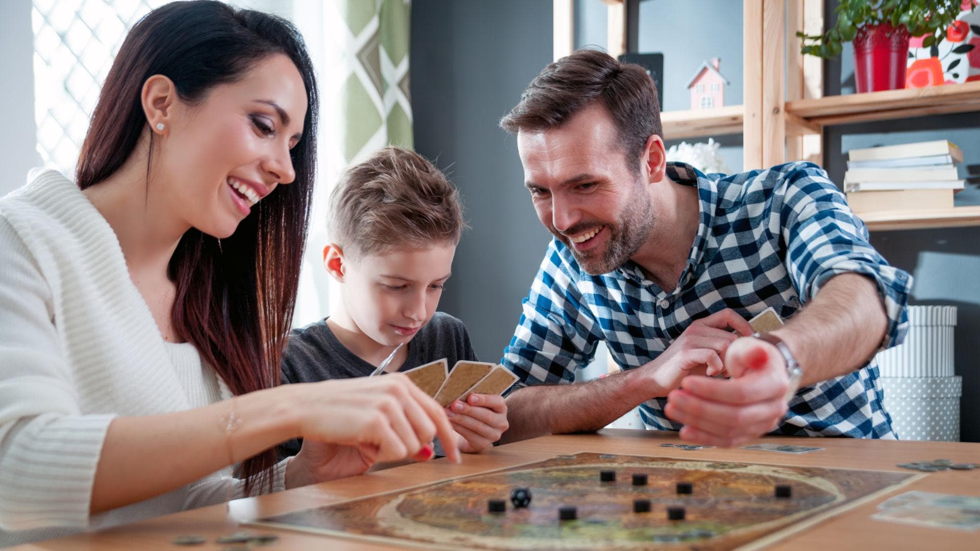 Familie_spielt_Spiel Familie sitzt am Tisch und spielt ein Brettspielt