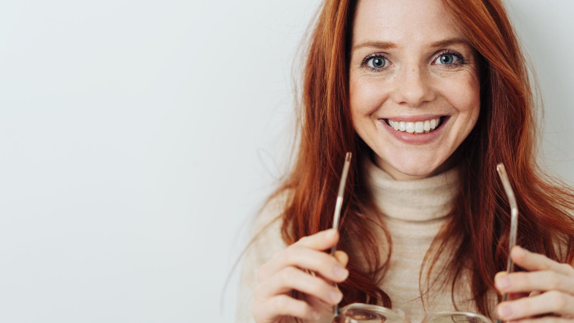 Frau mit strahlenden Augen und Brille in der Hand