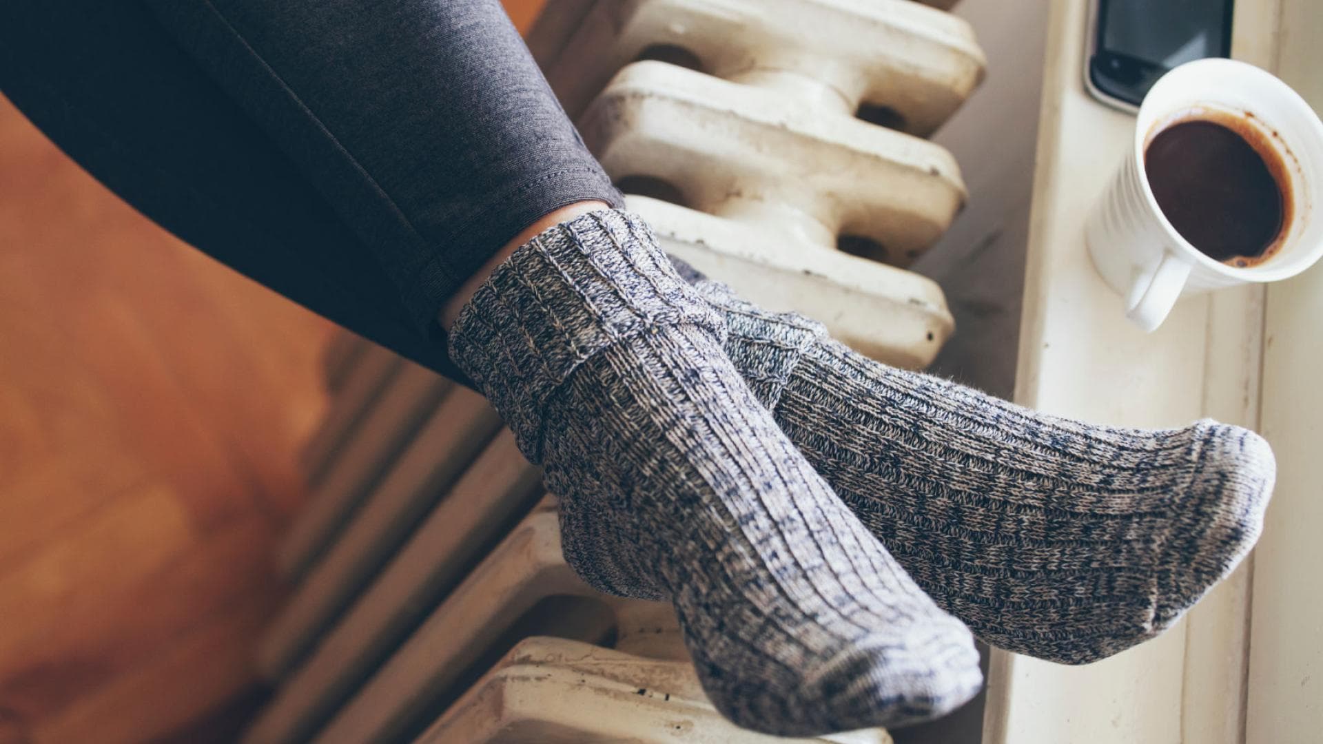 Frau mit Wollsocken Füße auf Heizung
