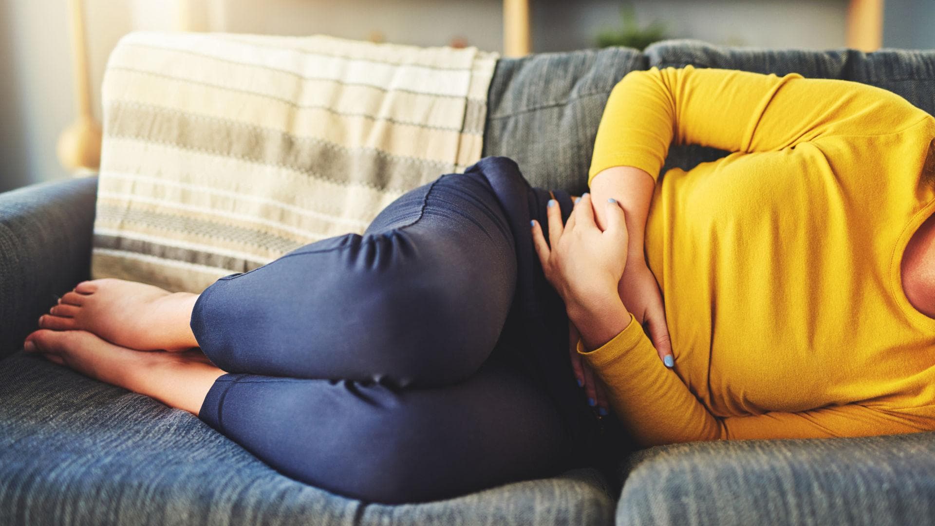 Frau mit Unterleibschmerzen auf dem Sofa