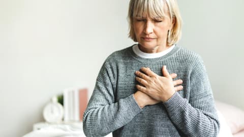 Frau fasst sich an die Brust