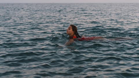 Frau schwimmt beim Sonnenuntergang im Meer