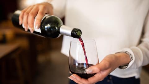 Frau schenkt sich ein Glas Wein ein