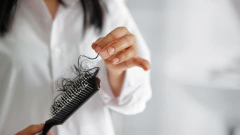 Frau mit Bürste, in der ein Haarbüschel steckt