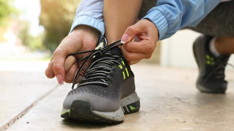 Eine Frau bindet sich die Schuhe zu