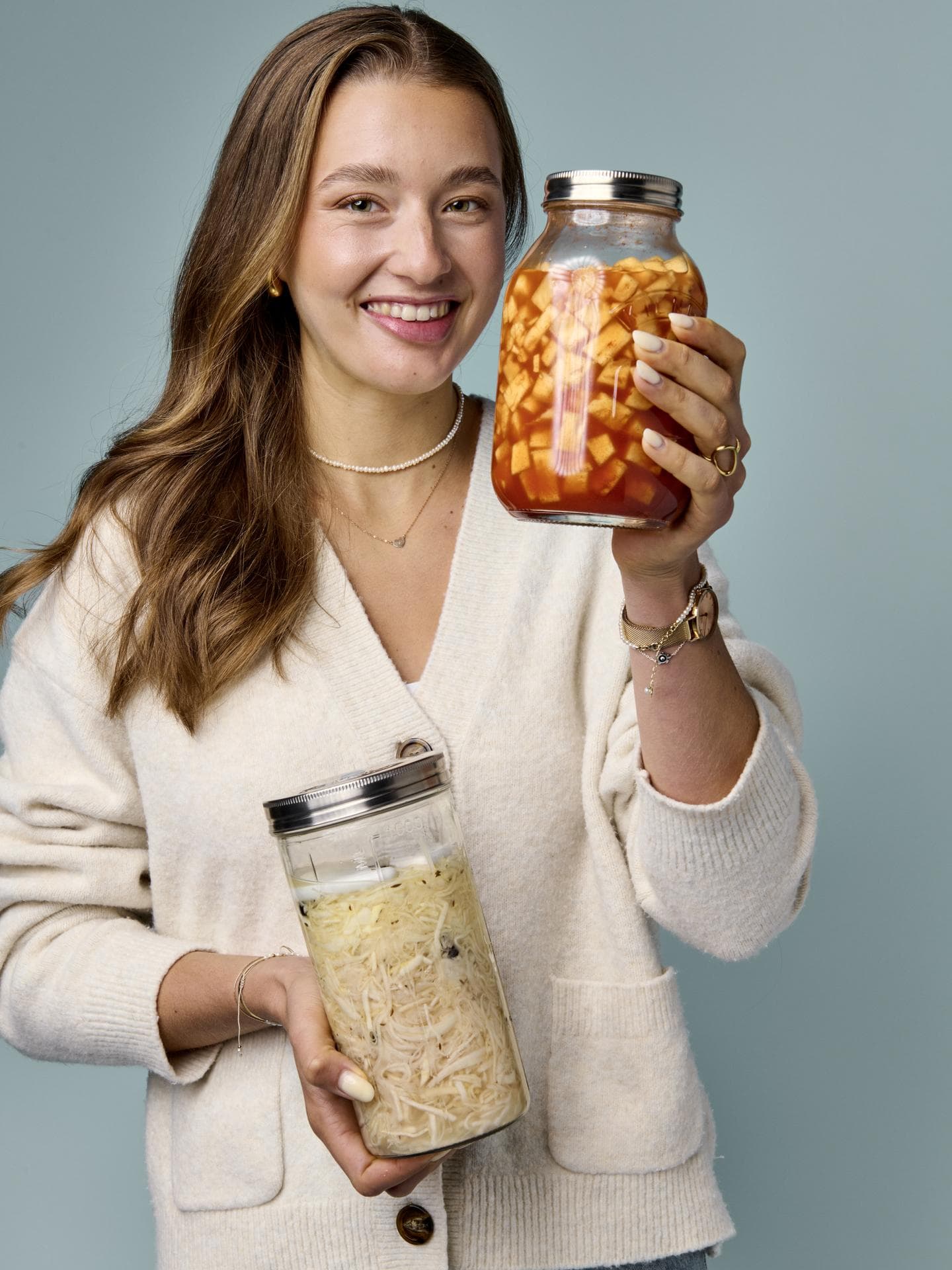 Maria Maas hält selbst fermentiertes Gemüse in Schaubgläsern in der Hand und lächelt in die Kamera