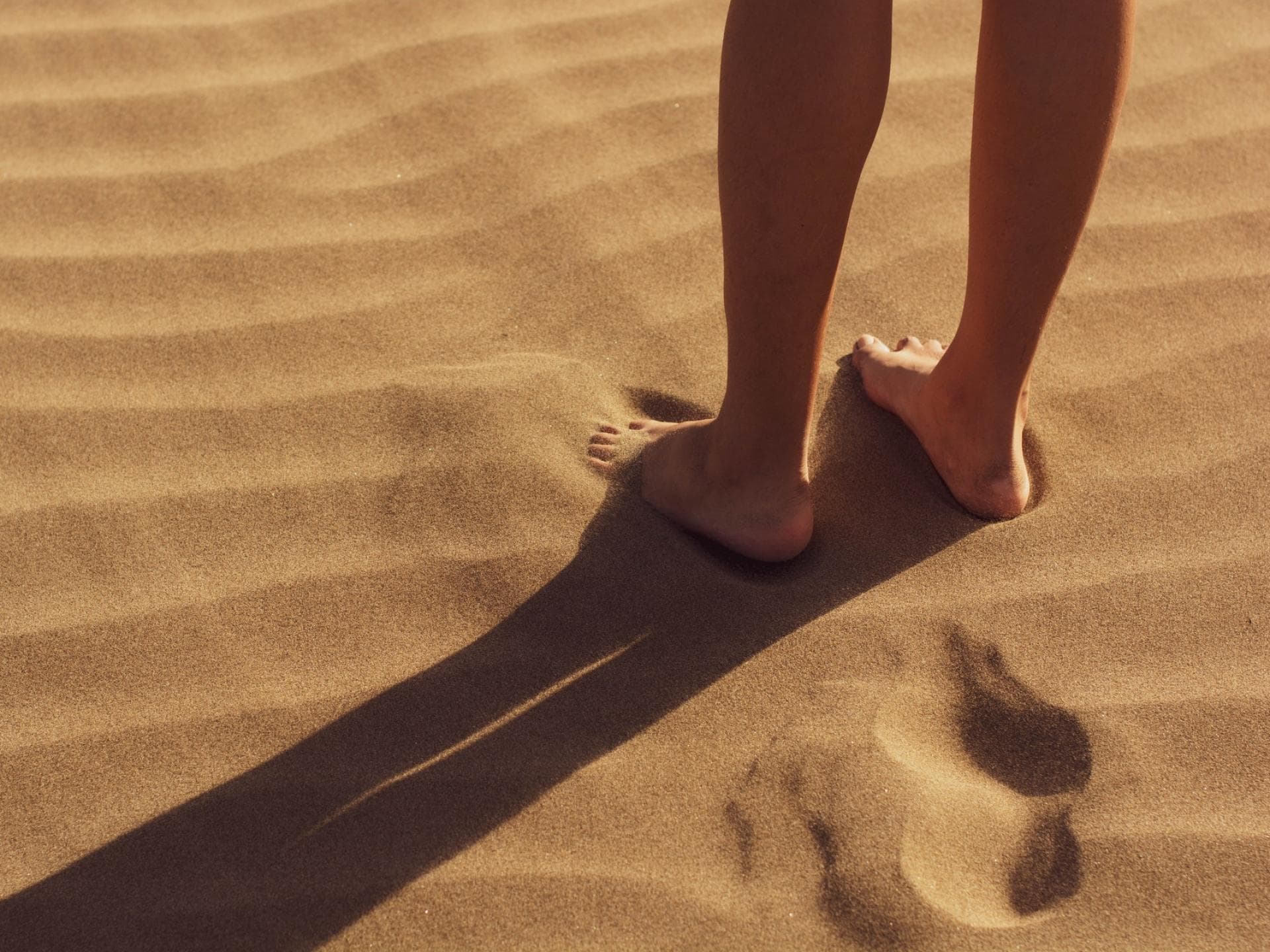 Frau steht barfuß im Sand