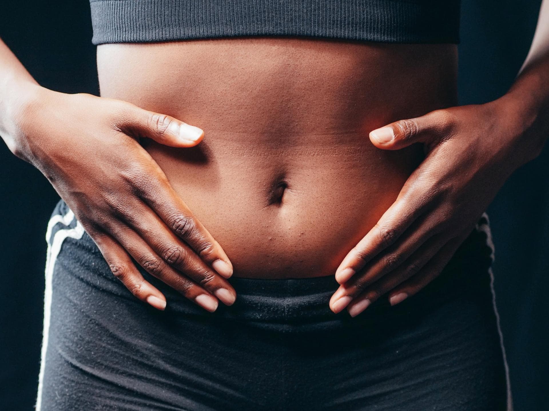 Frau legt Hände auf Ihren Bauch