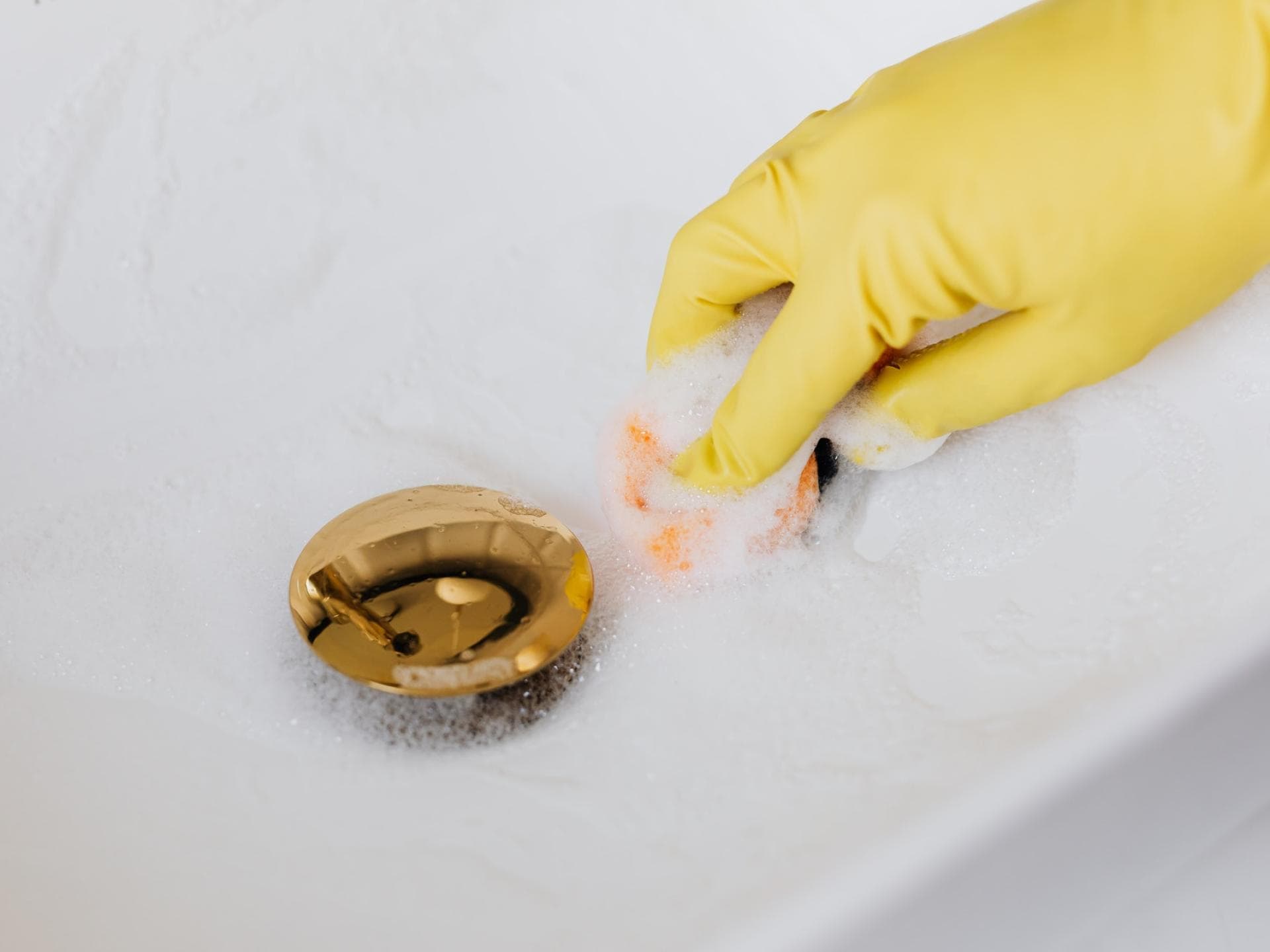 Mit Handschuhen das Waschbecken putzen