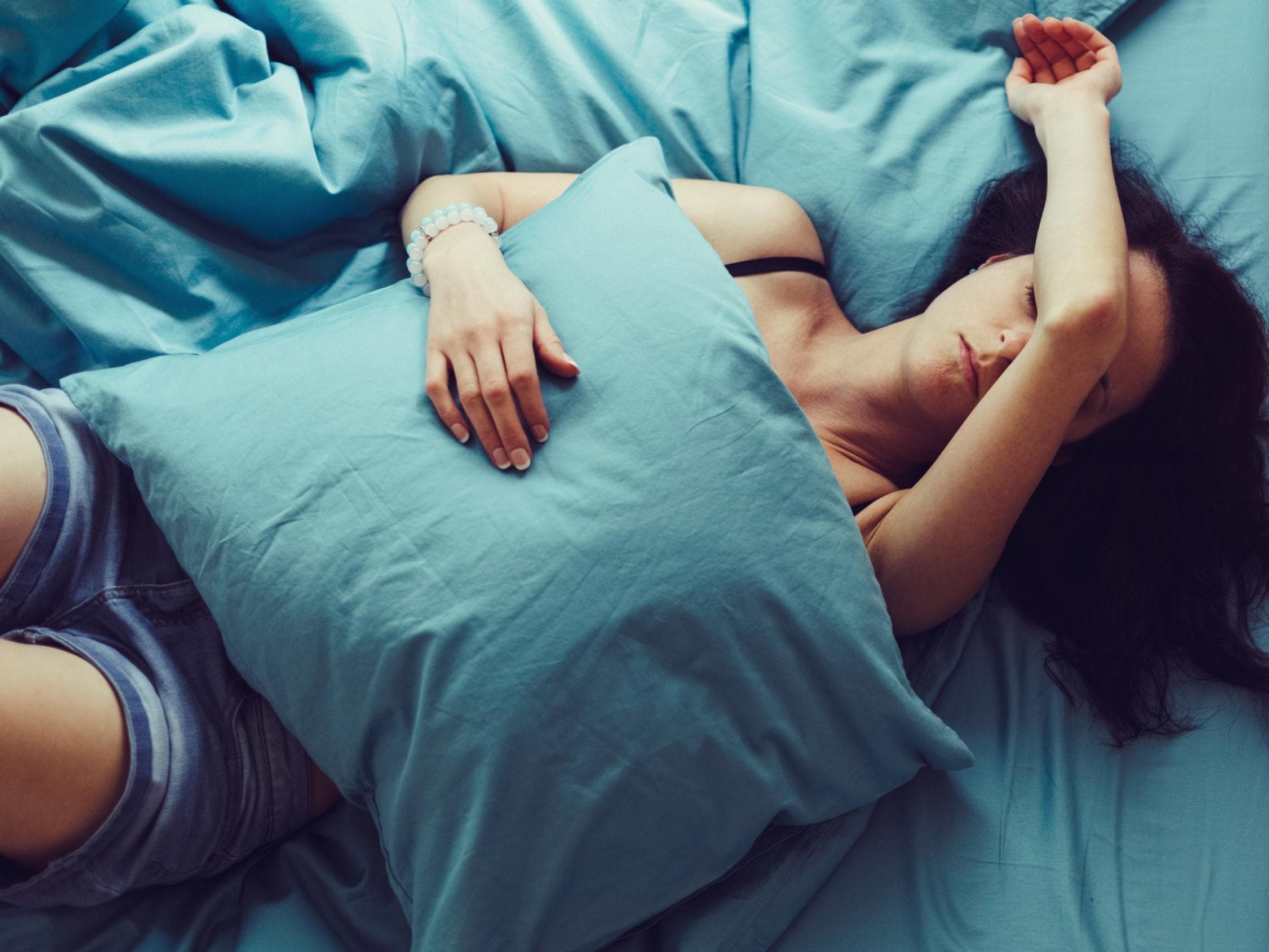 Frau liegt im Bett mit Kopfschmerzen