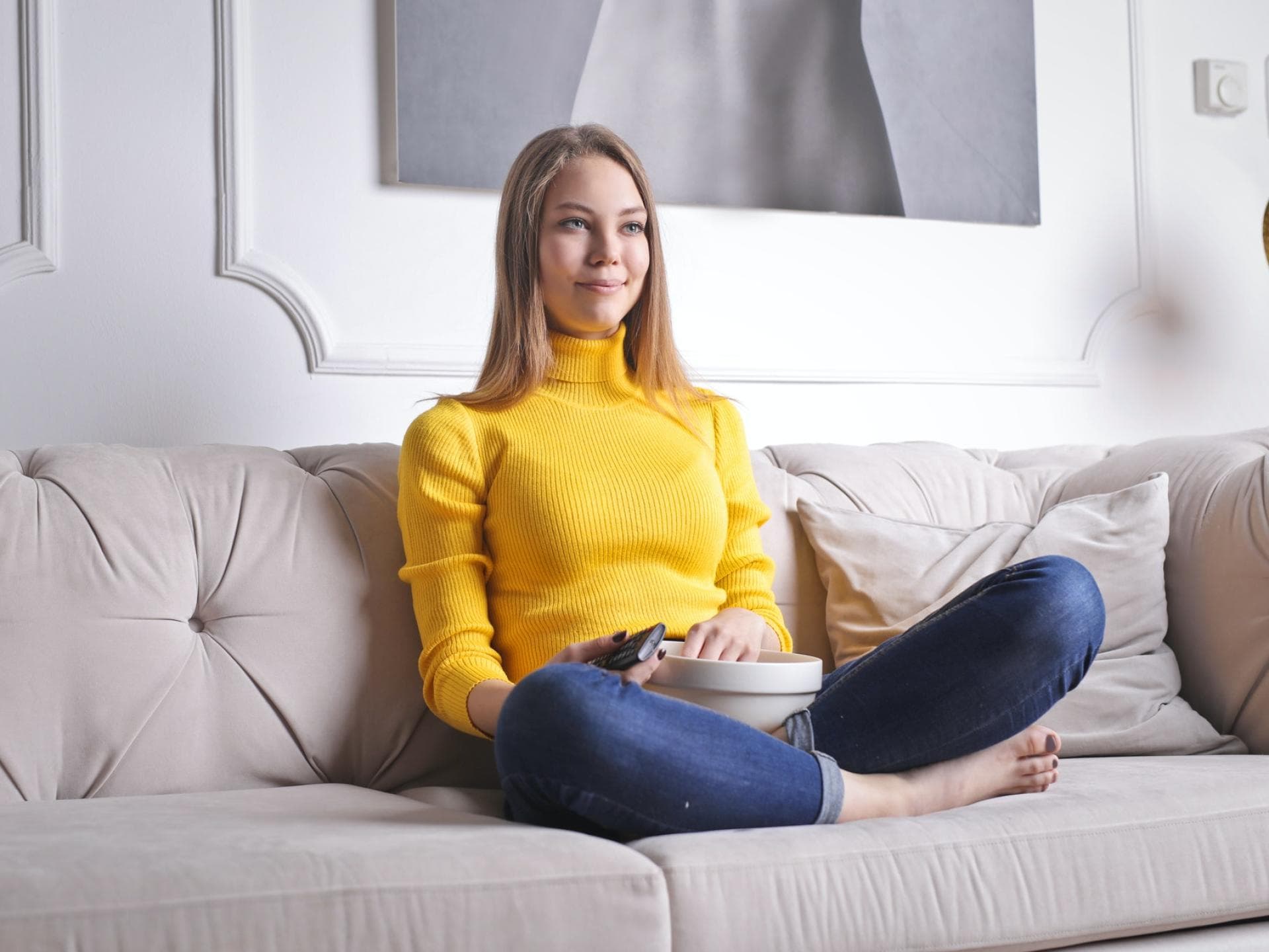 Frau sitzt auf Sofa und schaut Fernsehen.