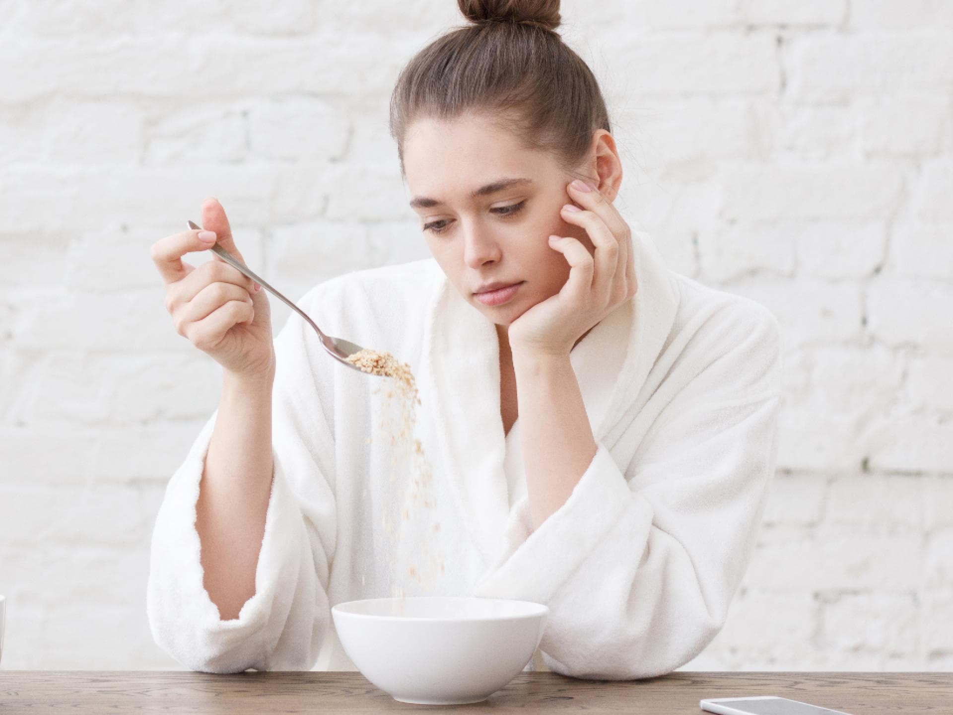 Frau schaut appetitlos auf ihr Müsli