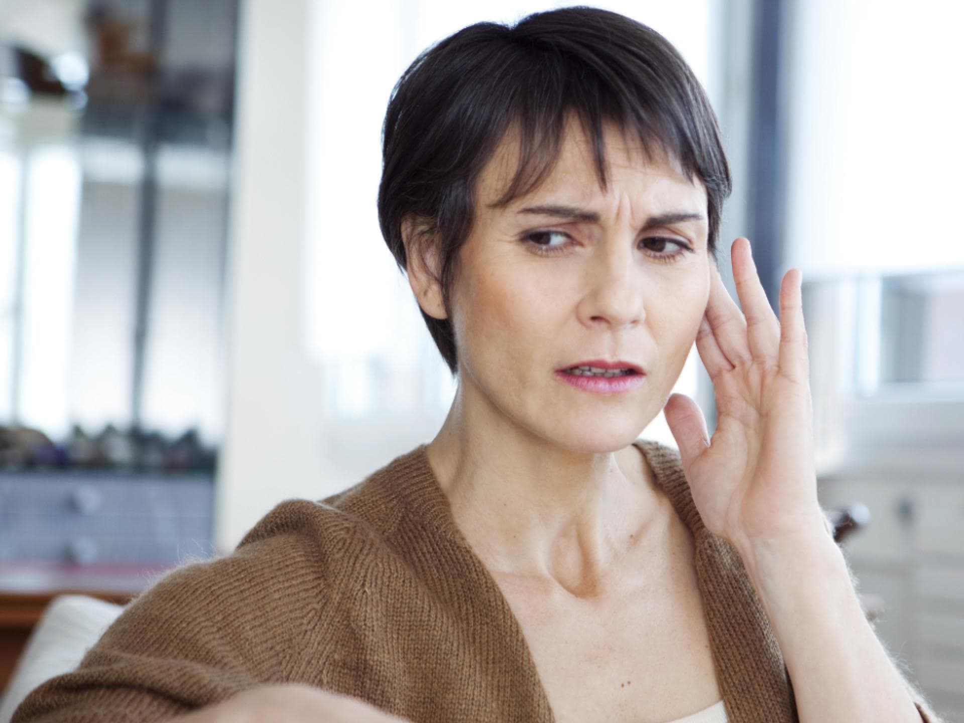 Eine Frau fasst sich vor Schmerzen ans Ohr