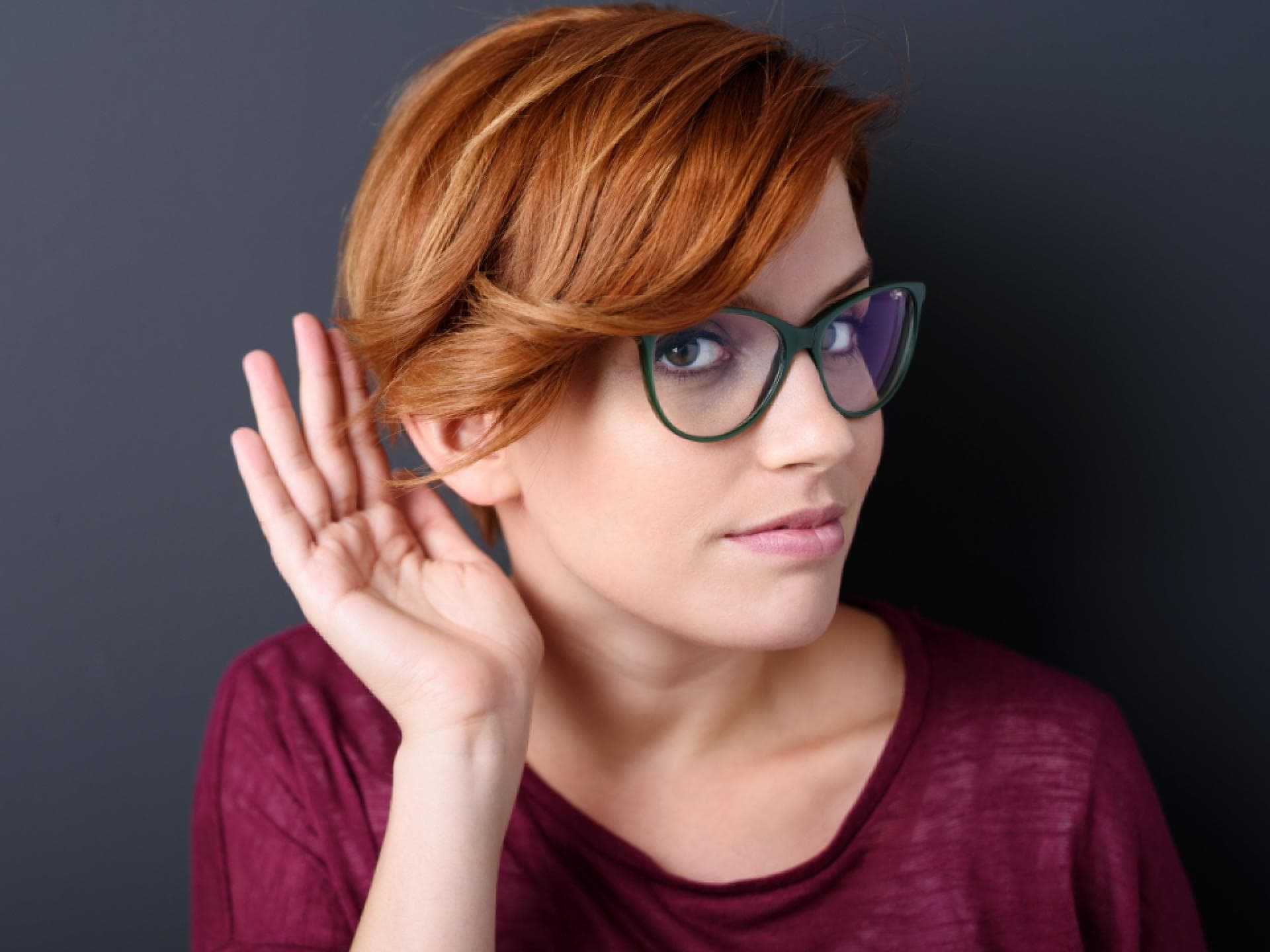 Frau hält sich eine Hand ans Ohr