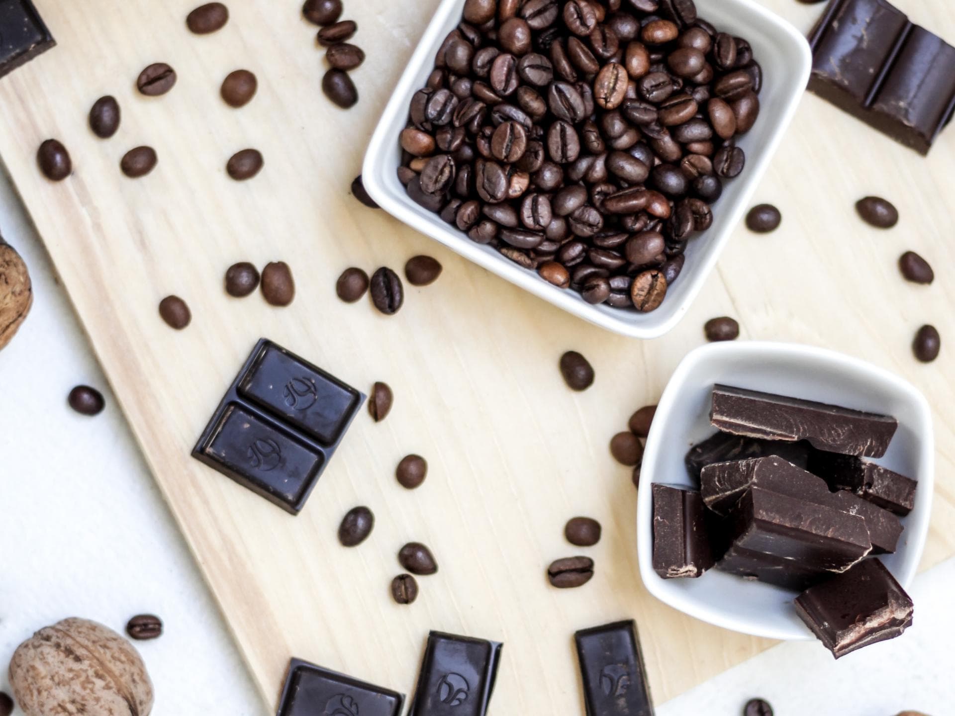 Zartbitterschokolade und Kaffee liefern gesunde Bitterstoffe Küchentischdisplay mit Zartbitterschokolade, Kaffeebohnen, Nüssen und Kakaopulver