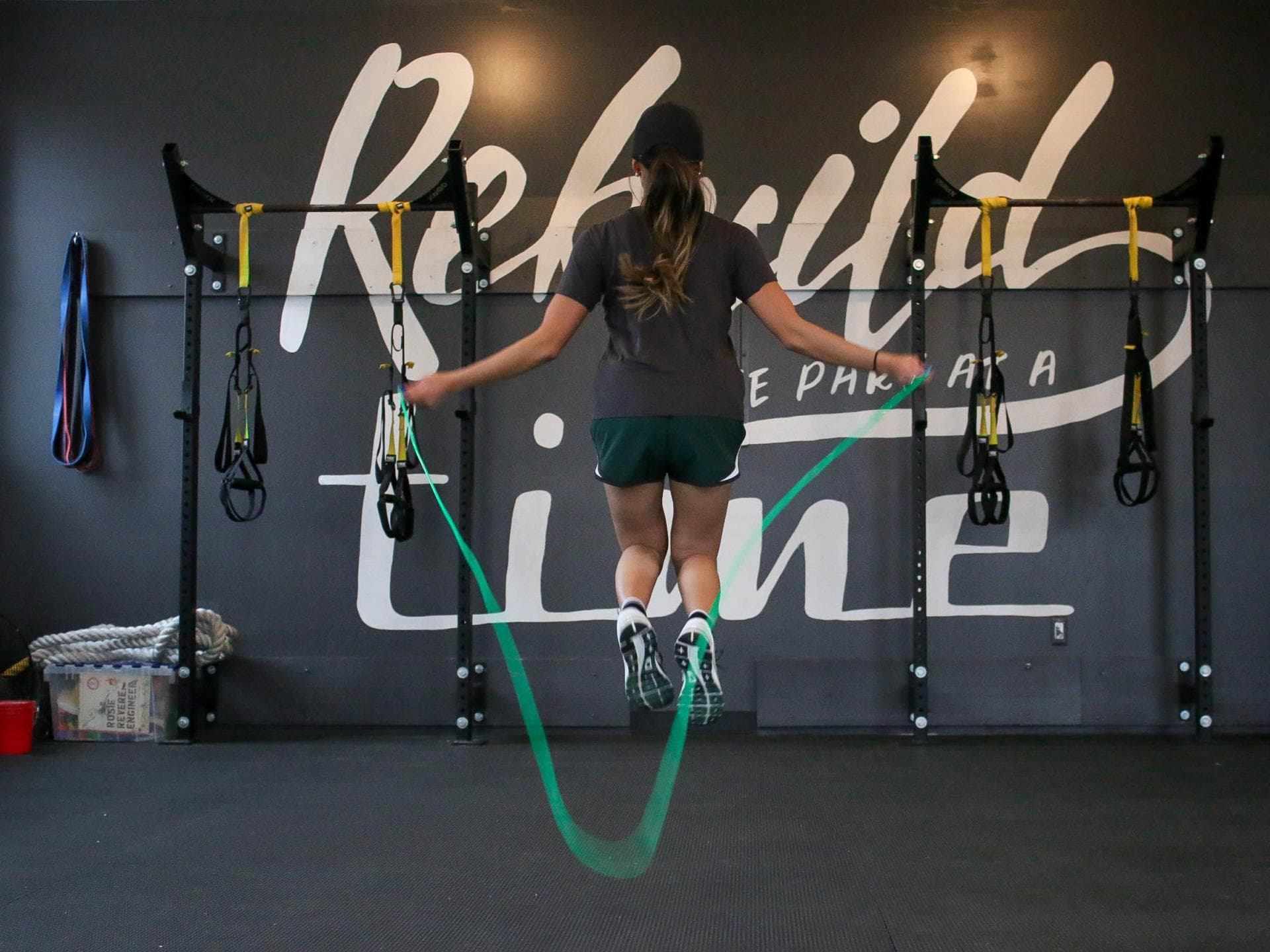 Frau beim Springseilspringen mit grünem Seil im Gym