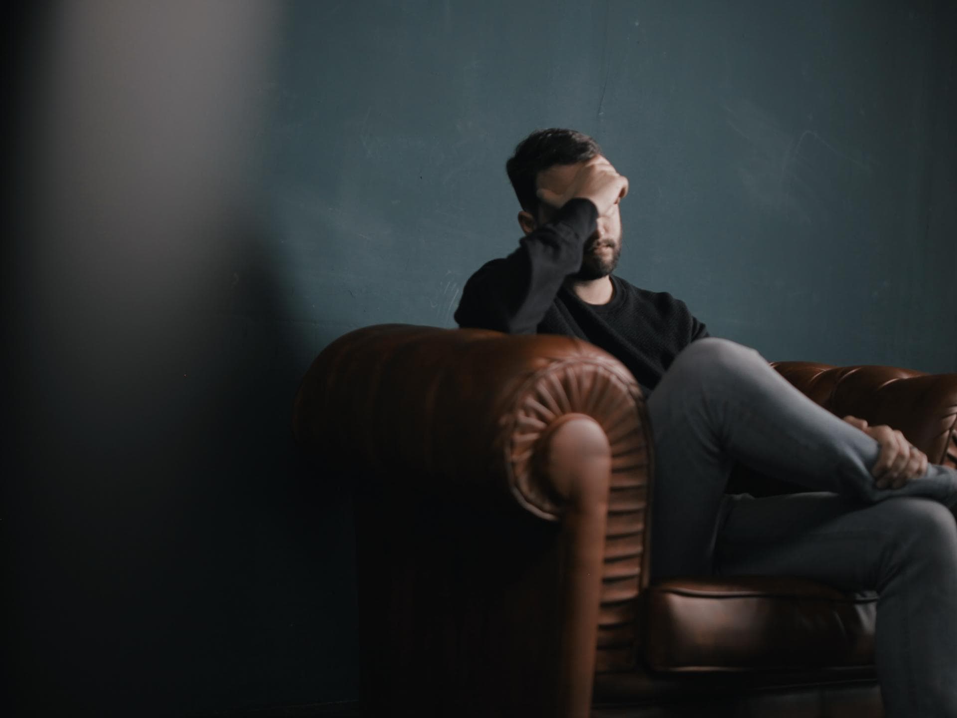 Mann mit Depressionen sitzt betrübt in Sessel