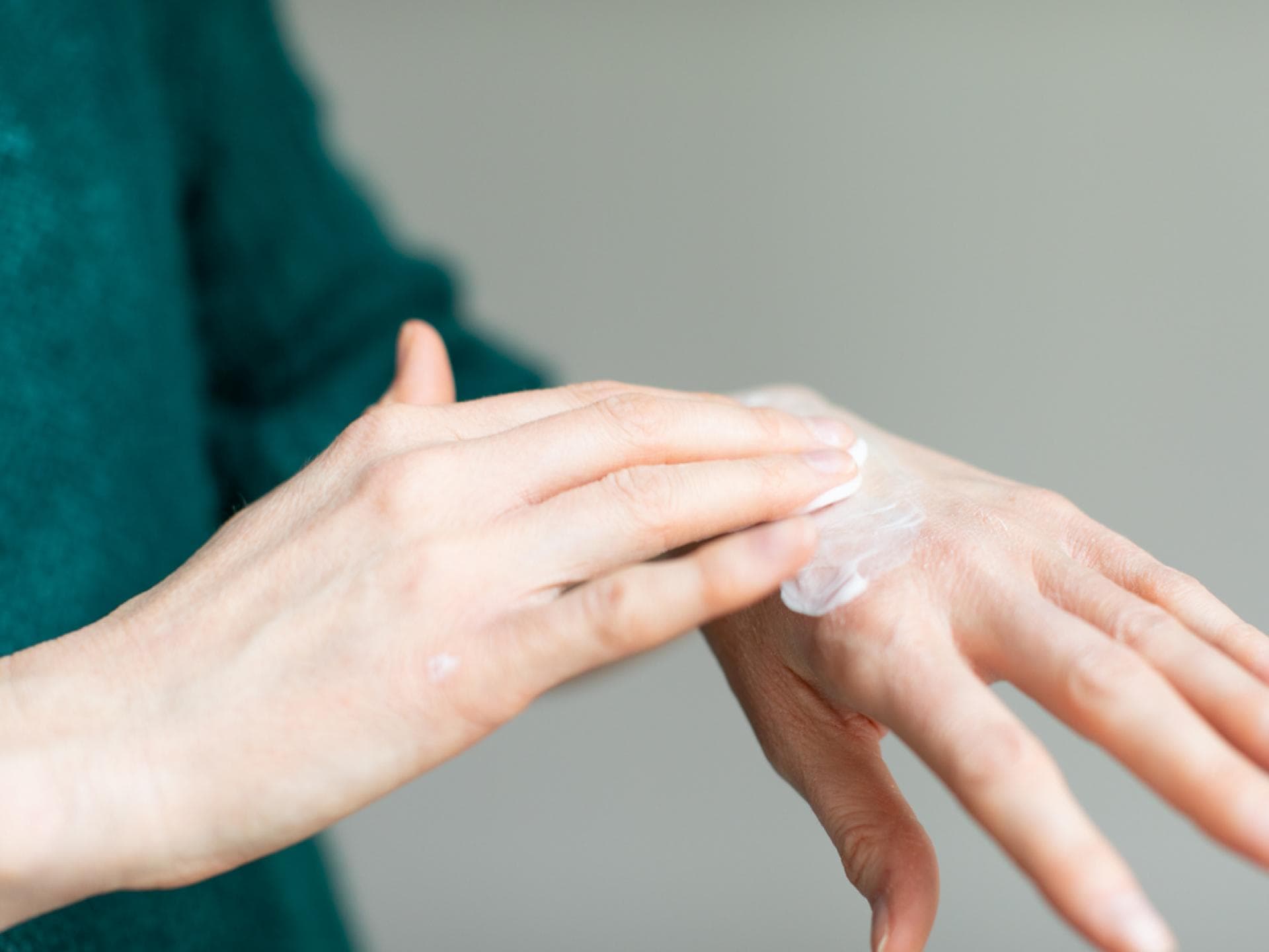 Frau trägt Creme auf Handrücken auf