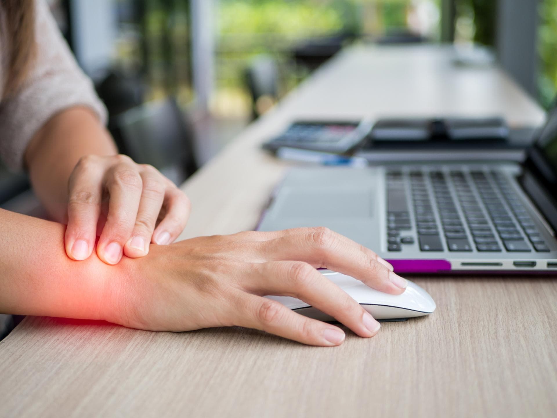 Frau im Büro mit Schmerz im Handgelenk