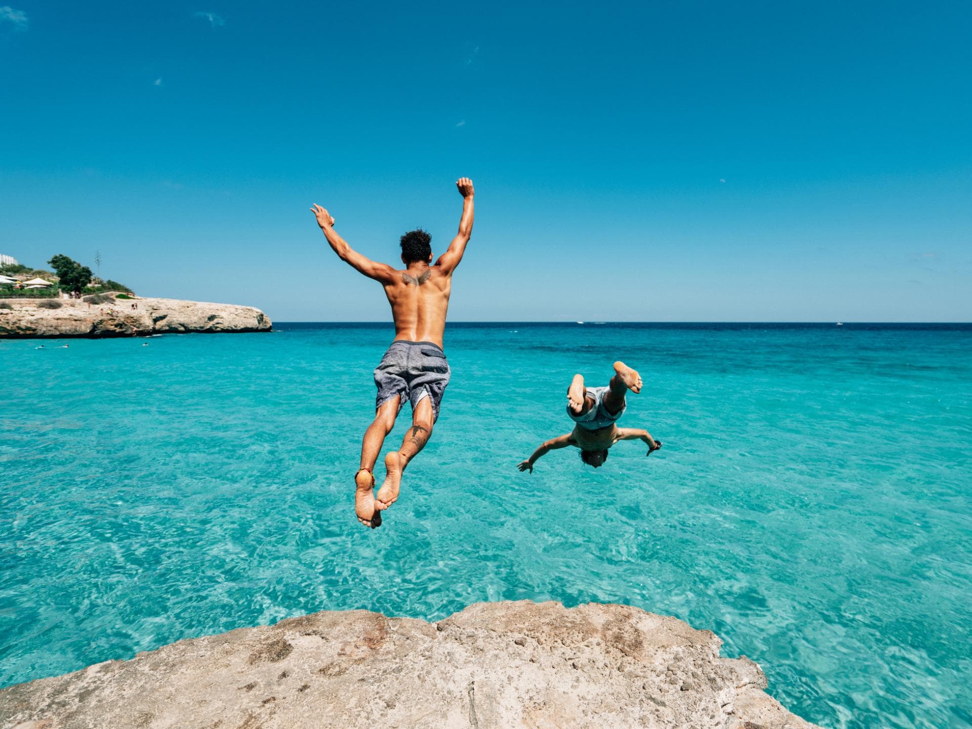 zwei junge Männer springen ins Meer