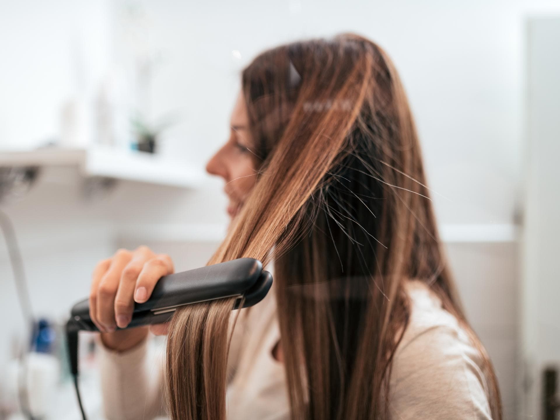 Frau glättet sich die Haare